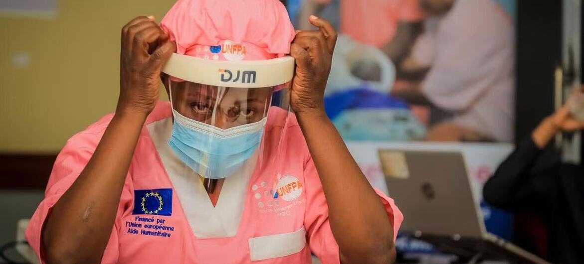 A female healthcare worker in the Democratic Republic of Congo adjusts her protective face shield and mask during an Ebola outbreak response.