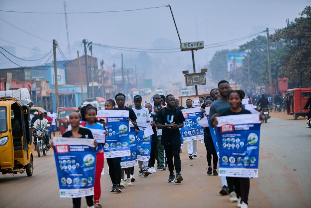 Un groupe de reporters d'U-Reporters défile dans une rue de Butembo, en République démocratique du Congo, brandissant des affiches bleues et blanches de sensibilisation à la prévention d'Ebola.