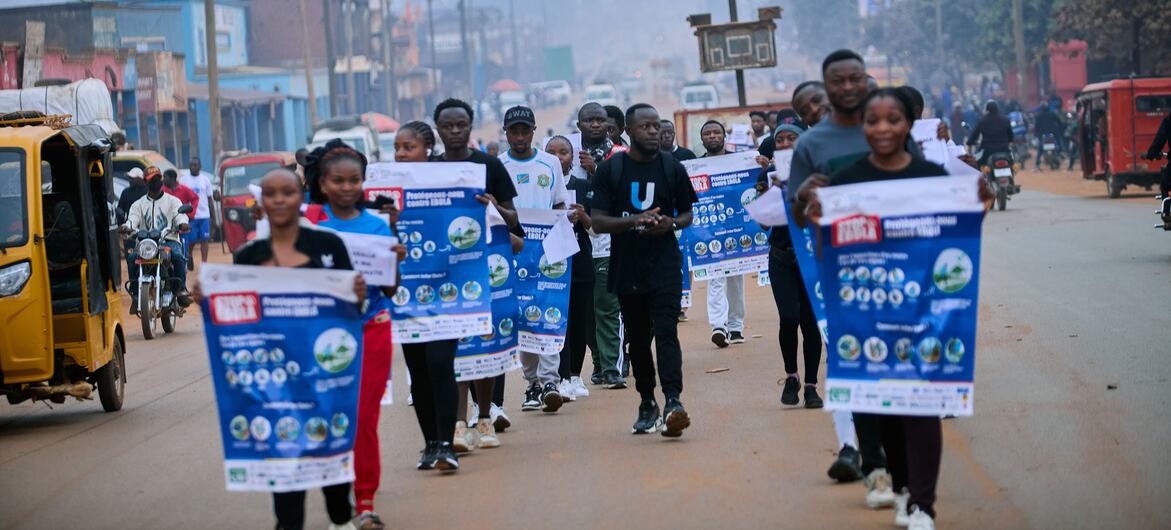 Un groupe de reporters d'U-Reporters défile dans une rue de Butembo, en République démocratique du Congo, brandissant des affiches bleues et blanches de sensibilisation à la prévention d'Ebola.
