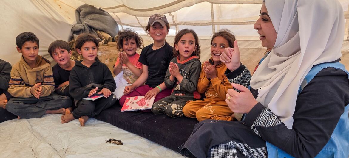 A UNICEF-supported mobile team member named Siba facilitates a personal safety awareness session with a group of children inside a tent at a camp in Mleihat, Dar’a Governorate, Syria.