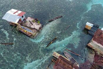 Aerial view of stilt houses and traditional boats in a coastal village in Papua New Guinea.