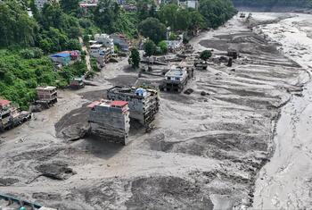 Vista aérea de un asentamiento nepalí en el distrito de Rasuwa cubierto por una espesa capa de lodo gris tras las inundaciones repentinas del 26 de agosto, con edificios de varios pisos dañados y escombros esparcidos por el paisaje.