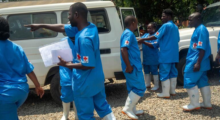 À Bunia, dans l'Ituri, une équipe de volontaires de la Croix-Rouge de la RDC, vêtus d'uniformes bleus et de bottes blanches, se tient près d'une camionnette blanche, se préparant pour une mission de lutte contre Ebola.