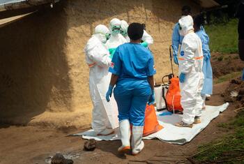 Des volontaires de la Croix-Rouge entièrement vêtus d'équipements de protection individuelle blancs et une infirmière en blouse bleue procèdent à l'inhumation sécurisée d'un nourrisson à Bembei, dans l'Ituri, en RDC, lors d'une épidémie d'Ebola.