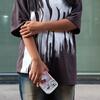 Une jeune fille vêtue d'un t-shirt à motifs et d'un jean se tient dans une rue de Phnom Penh, tenant un téléphone avec une coque Hello Kitty.