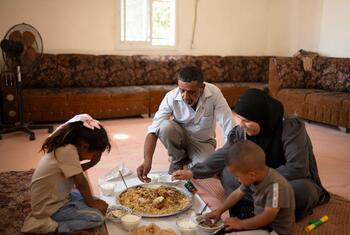 Palestinian Bedouin family shares a meal on the floor of their living room in Um Alkhair, West Bank, as part of WFP and UNRWA food assistance program amid escalating settler tensions.
