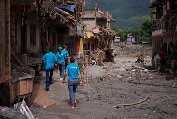 Des employés de l'UNICEF parcourent les rues dévastées d'une ville du Népal détruite par des inondations.
