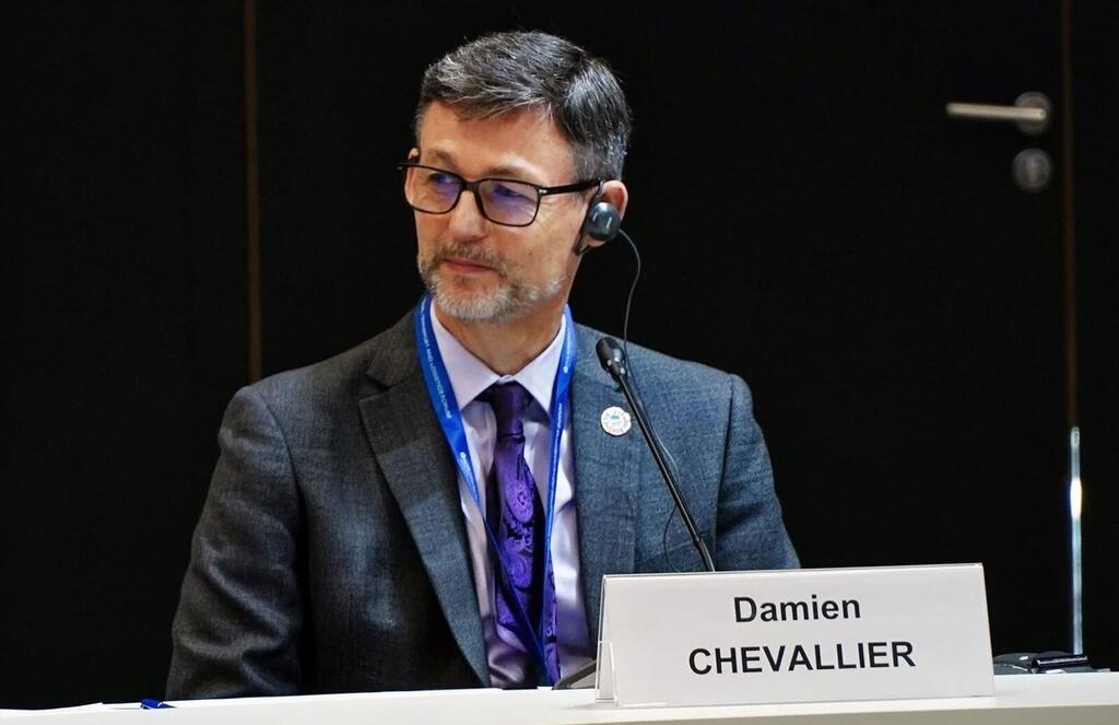 Damien Chevallier, director de la División de Seguridad Marítima de la Organización Marítima Internacional (IMO), sentado en una mesa de conferencias con una placa con su nombre delante.
