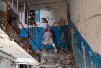 Fourteen-year-old Sofiia, her leg bandaged, walks carefully down the rubble-covered stairwell of her damaged apartment building in Boryspil, Ukraine, after an overnight missile attack.
