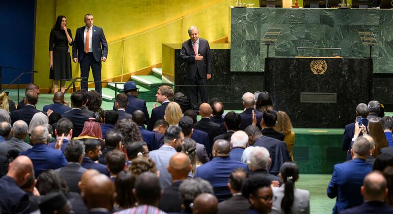 UN Secretary-General António Guterres stands near the podium as delegates applaud after his address in the United Nations main hall.