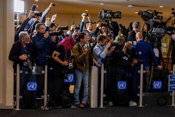 Photographers and video journalists with cameras and telephoto lenses crowd a press pool barrier at the United Nations headquarters in New York as delegates and heads of state arrive.
