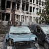 À Kyiv, en Ukraine, deux voitures accidentées gisent devant un immeuble de bureaux à plusieurs étages, aux fenêtres brisées et aux murs noircis par la suie.