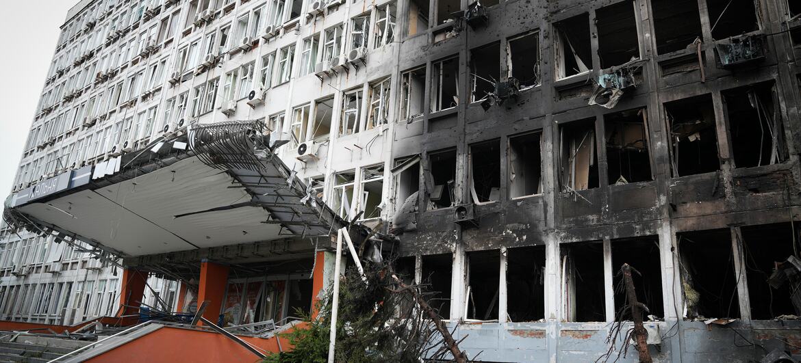 Un edificio de oficinas de varias plantas en Kiev, Ucrania, con la fachada chamuscada, las ventanas rotas y la marquesina de la entrada derrumbada tras un ataque.