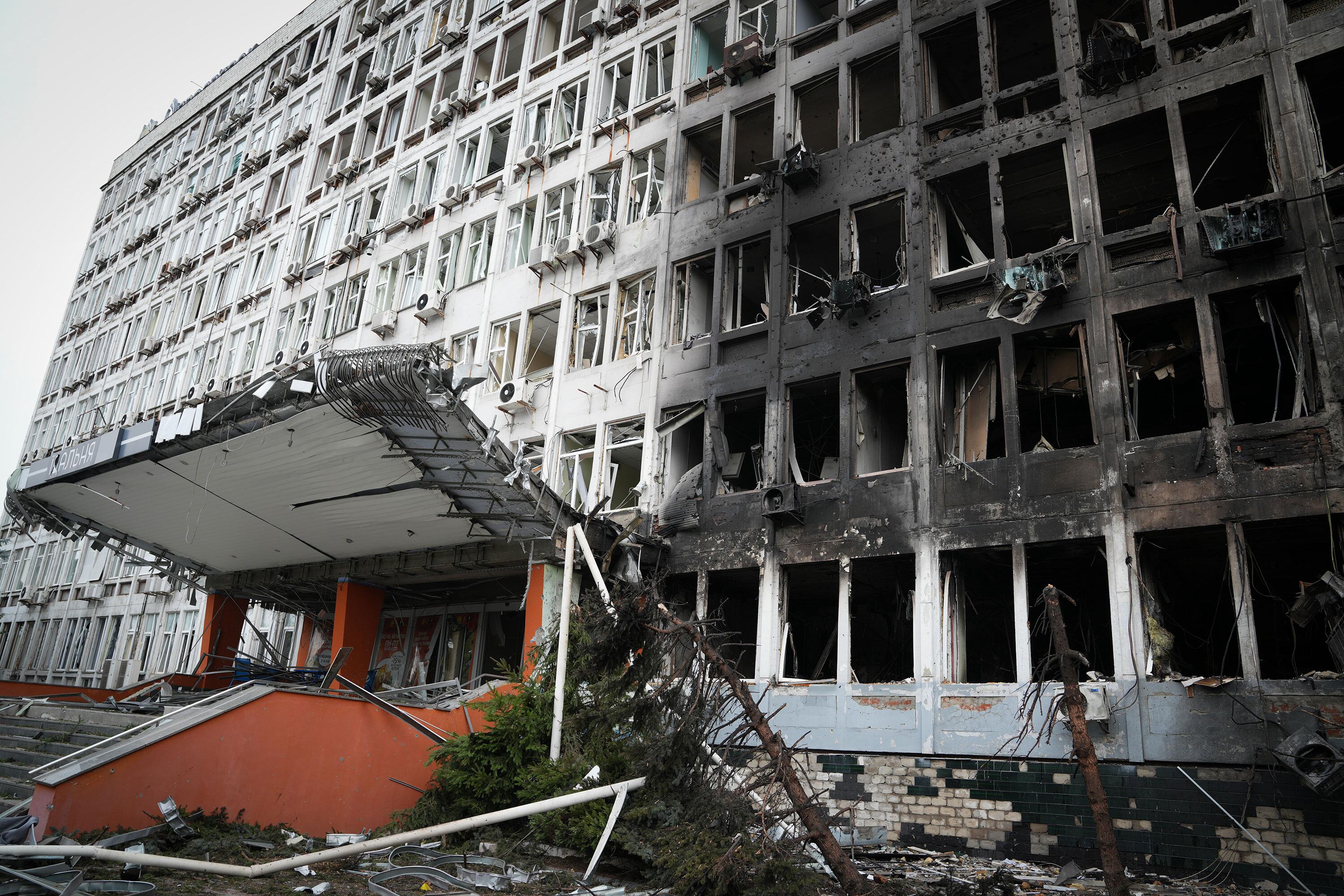 A multi-story office building in Kyiv, Ukraine, with a scorched facade, broken windows, and a collapsed entrance canopy after an attack.