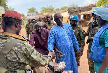 A soldier in camouflage uniform with a red beret shakes hands with a man in a blue traditional robe during a joint patrol by UN troops and Central African forces in a market area of Birao, Vakaga prefecture.