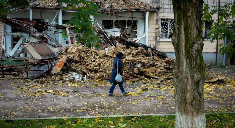 यूक्रेन के बोरोडियांका में एक नष्ट घर के पास से गुज़रती एक महिला