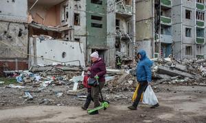 People walk past bomb-damaged building in Chernihiv in northern Ukraine.