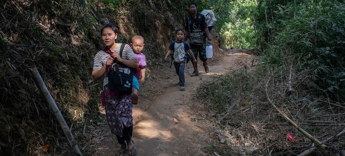 Uma família deslocada internamente no leste de Mianmar caminha perto da fronteira com a Tailândia