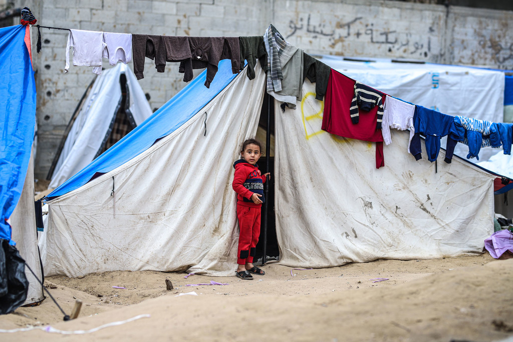 Msichana, ambaye familia yake imekimbia mzozo huo, anasimama nje ya hema lake huko Rafah, Gaza.