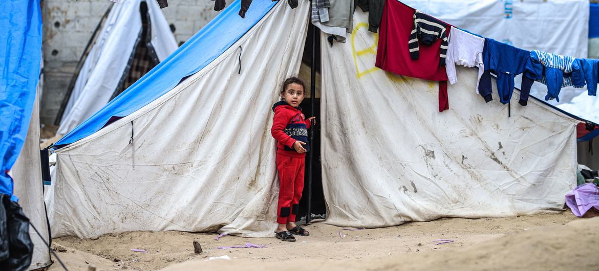 一名女孩站在加沙拉法的帐篷外，她和家人因冲突而流离失所。