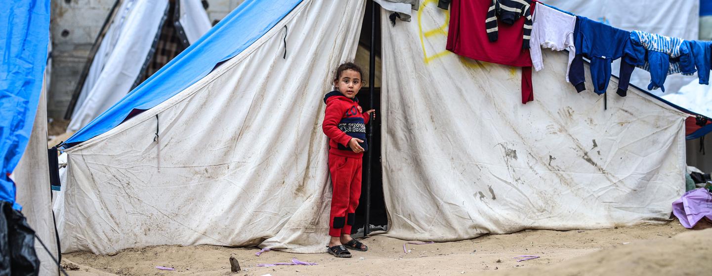 Une jeune fille, dont la famille a été déplacée par le conflit, se tient à l'extérieur de sa tente à Rafah, Gaza.
