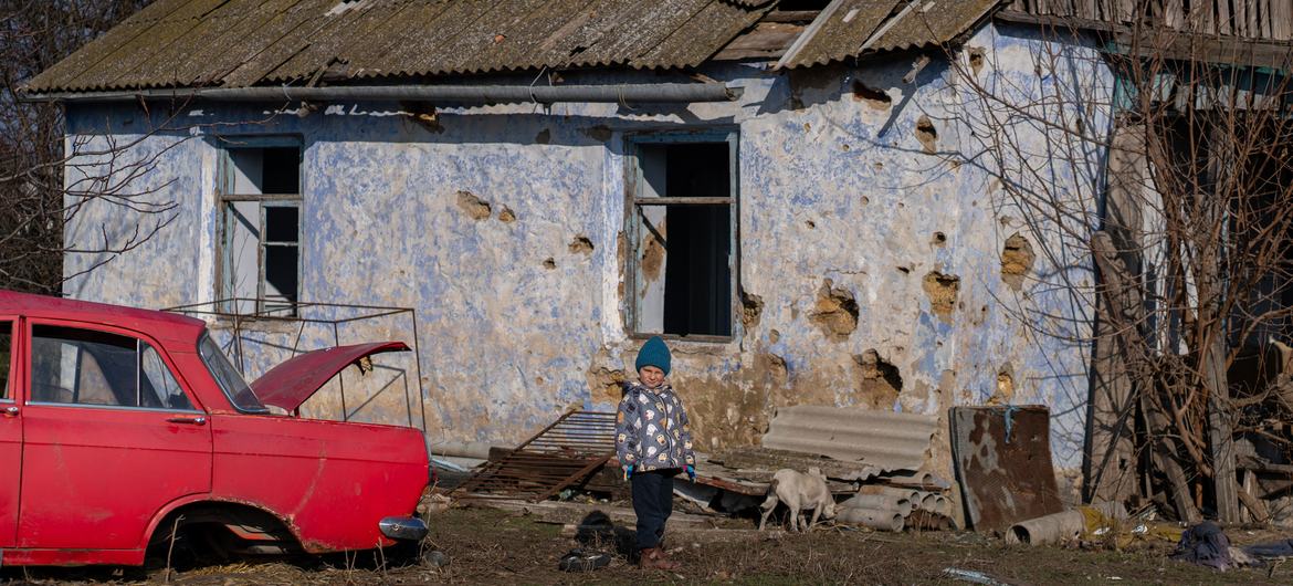 Roma, de 4 anos, em frente à sua casa destruída em Kobzartsi, região de Mykolaiv