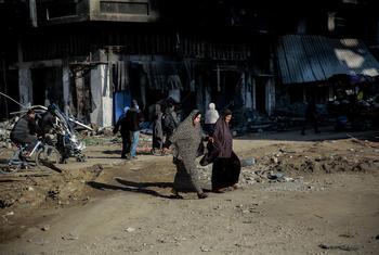 امرأتان تعبران شارعا مدمرا في مدينة غزة.