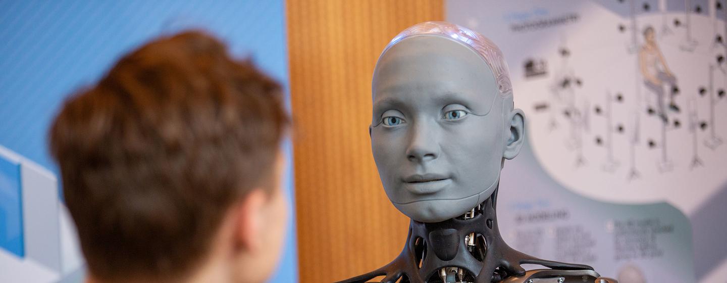 Un jeune homme observe Ameca, un robot humanoïde, lors d'une exposition à Genève.