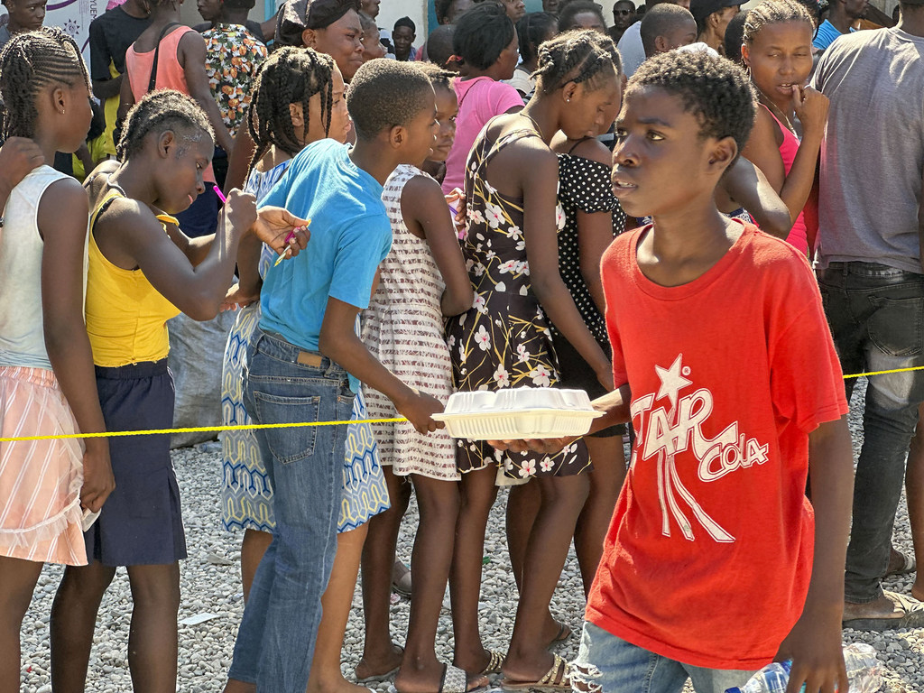 Children in Haiti line up for a hot meal and water distributed by WFP in Port-au-Prince.