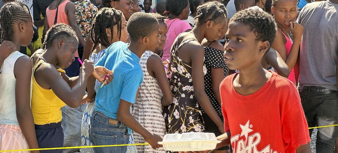 Crianças no Haiti fazem fila para uma refeição quente e água distribuída pelo PMA em Porto Príncipe