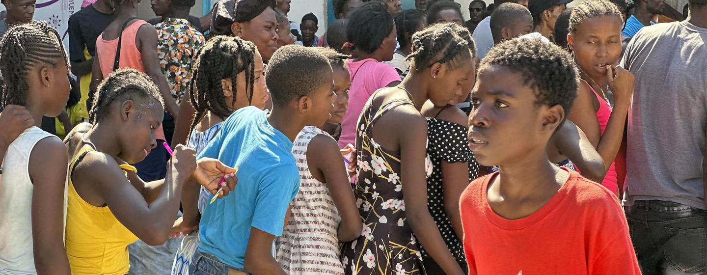 海地儿童在太子港排队领取粮食计划署分发的热餐和水。