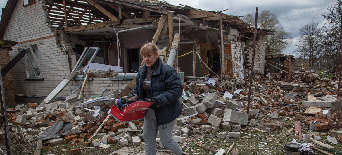 Seorang wanita mengambil barang-barang dari rumahnya yang dibom di desa Novoselivka, dekat Chernihiv, Ukraina.