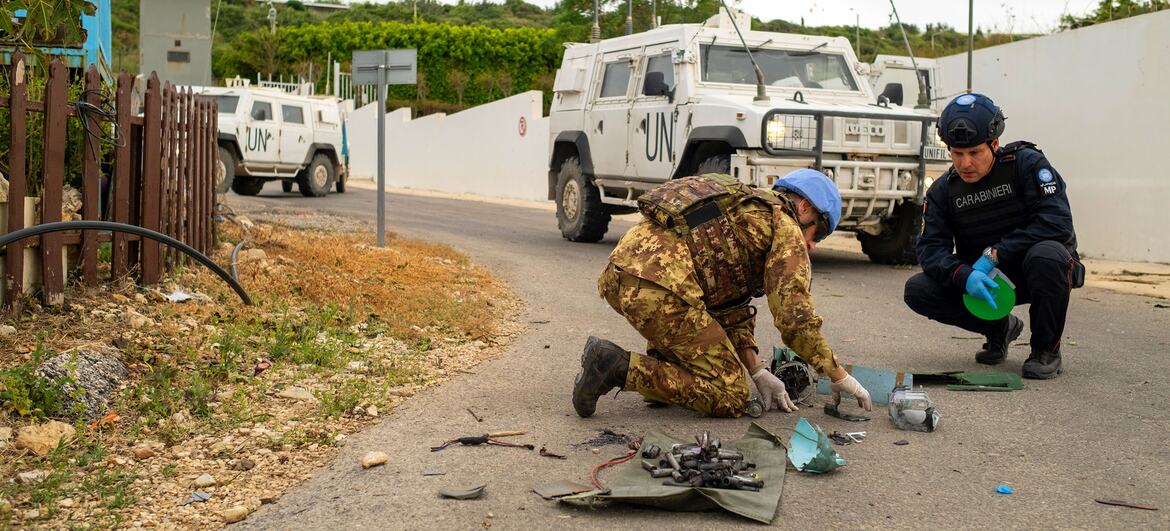 A UNIFIL forensic investigator and an Italian Carabinier examine drone remnants on the ground near a road in Naqoura.