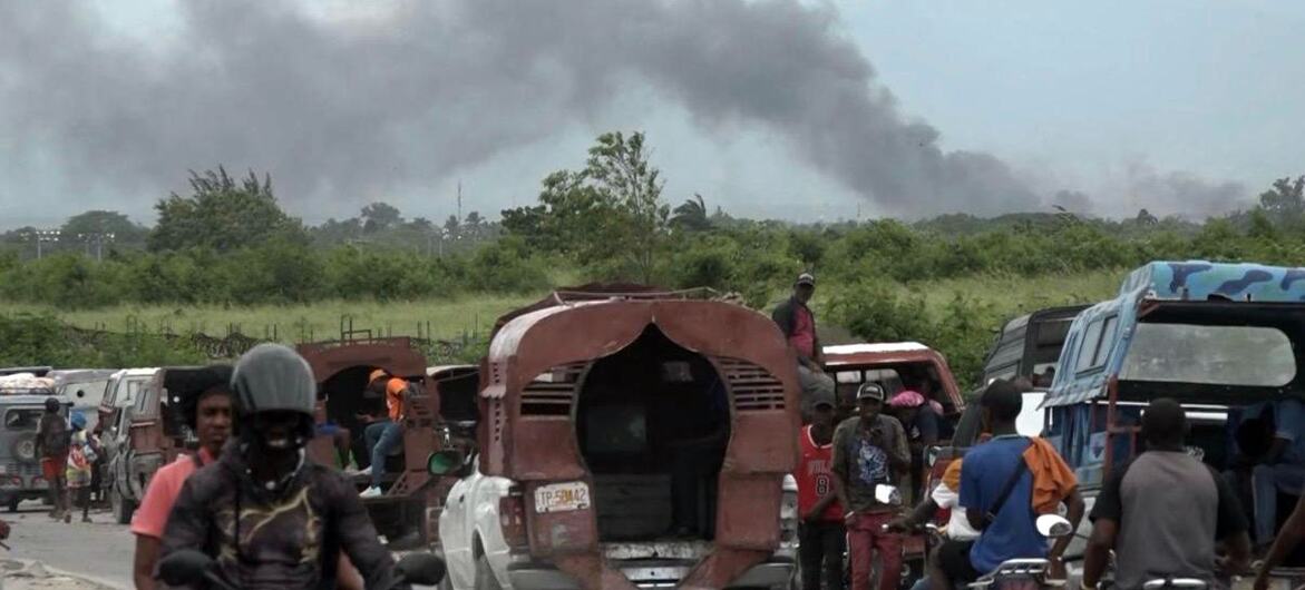 Residents flee from Cité Soleil to Drouillard in Port-au-Prince, Haiti, as thick smoke rises in the background from clashes between armed groups.