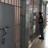 一名女狱警正在检查伊利甘市监狱女子宿舍牢房的铁栏杆。