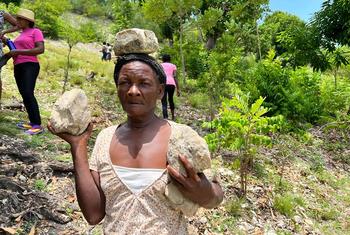 Une femme apporte des pierres pour construire des barrières contre les inondations.