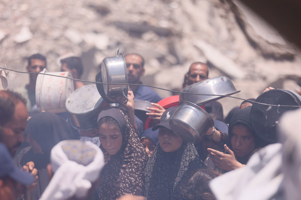 People in Gaza wait for food at a communal kitchen.