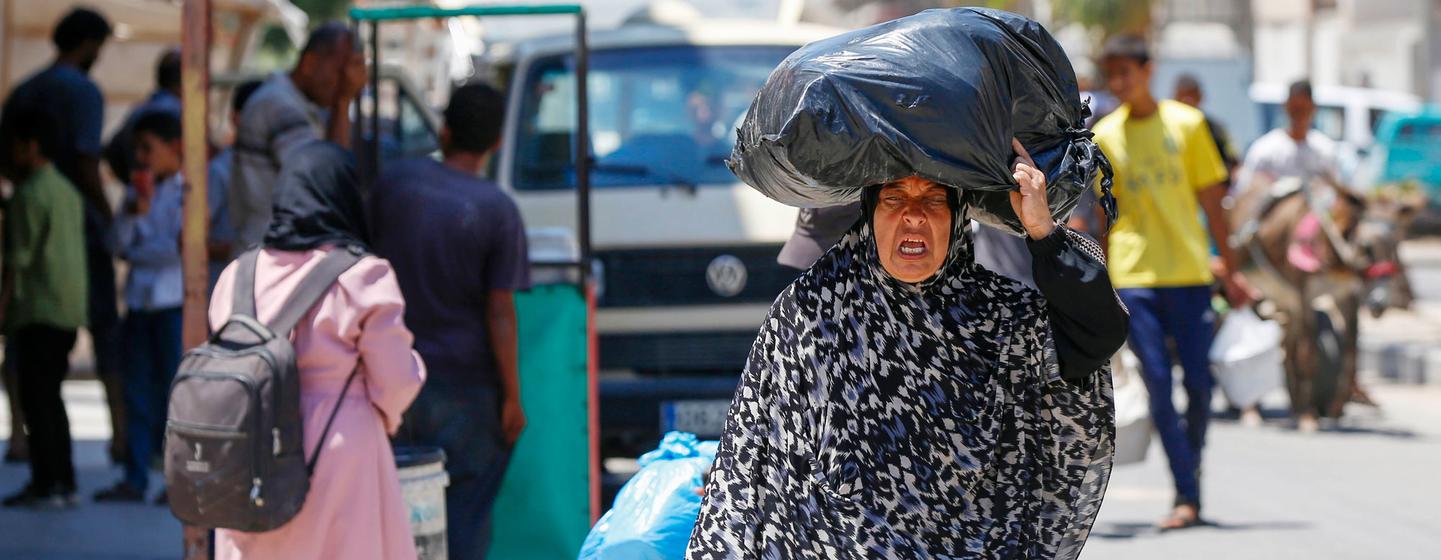 Une Palestinienne portant un grand sac noir sur la tête, évacuant avec d'autres familles de Deir Al-Balah, dans la bande de Gaza.