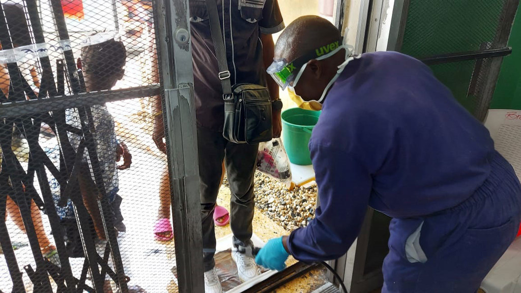 Un agent de santé effectue des procédures d'assainissement alors que des personnes entrent dans un établissement de soins contre le choléra en Haïti.