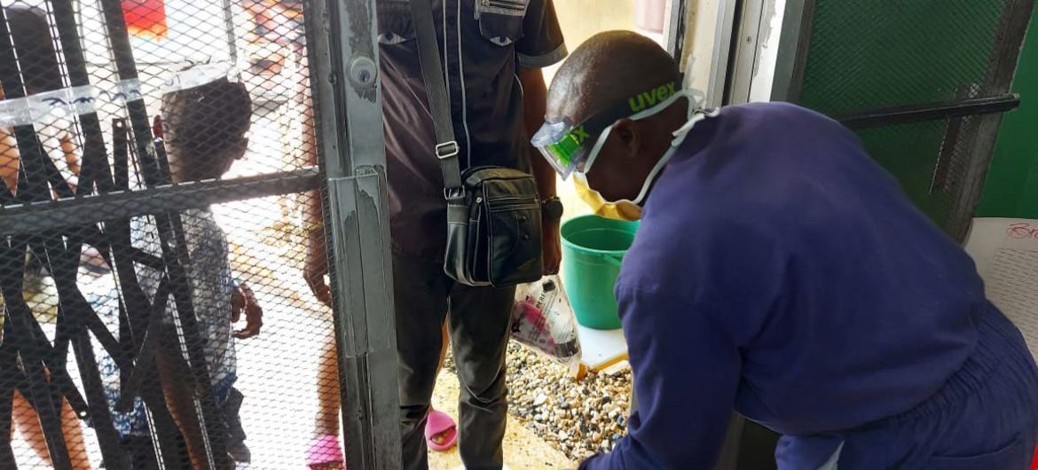 A health worker carries out sanitation procedures as people enter a cholera facility in Haiti.