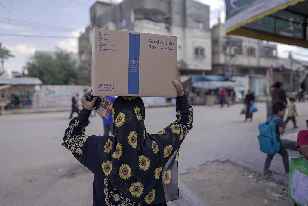 Une femme porte un colis alimentaire du Programme alimentaire mondial (PAM) à Almaghazi, dans le centre de Gaza.