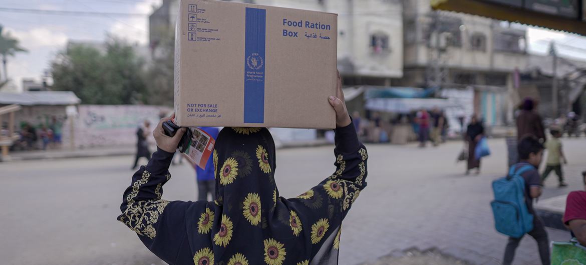 Une femme porte un colis alimentaire du Programme alimentaire mondial (PAM) à Almaghazi, dans le centre de Gaza.