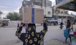 A woman carries food rations distributed by the World Food Programme in Almaghazi, Gaza.