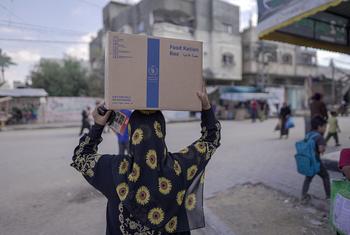 A woman carries food rations distributed by the World Food Programme in Almaghazi, Gaza.