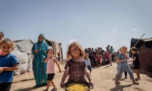 A young girl carries a pot of cooked food in Al-Mawasi, Gaza. 
