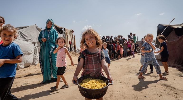 A young girl carries a pot of cooked food in Al-Mawasi, Gaza. 