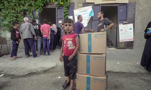 Un niño pequeño junto a tres cajas de alimentos distribuidos por la ONU, los primeros que su familia recibe en los últimos seis meses.