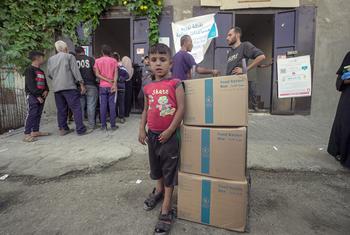 Un niño pequeño junto a tres cajas de alimentos distribuidos por la ONU, los primeros que su familia recibe en los últimos seis meses.
