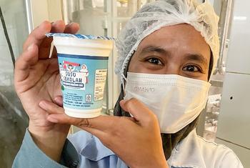A worker at the KPBS cooperative holds up a dairy product.  