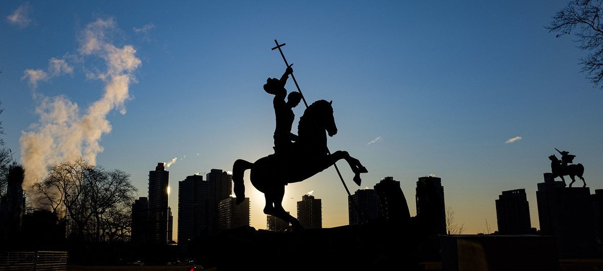 Вид на восходящее солнце позади Лонг-Айленд-Сити и скульптуру Зураба Церетели "Добро побеждает зло"